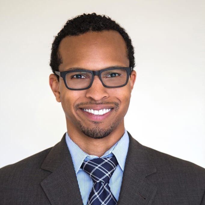 Headshot of black-owned business co-founder Biffrey Braxton, man in suit with glasses smiling.