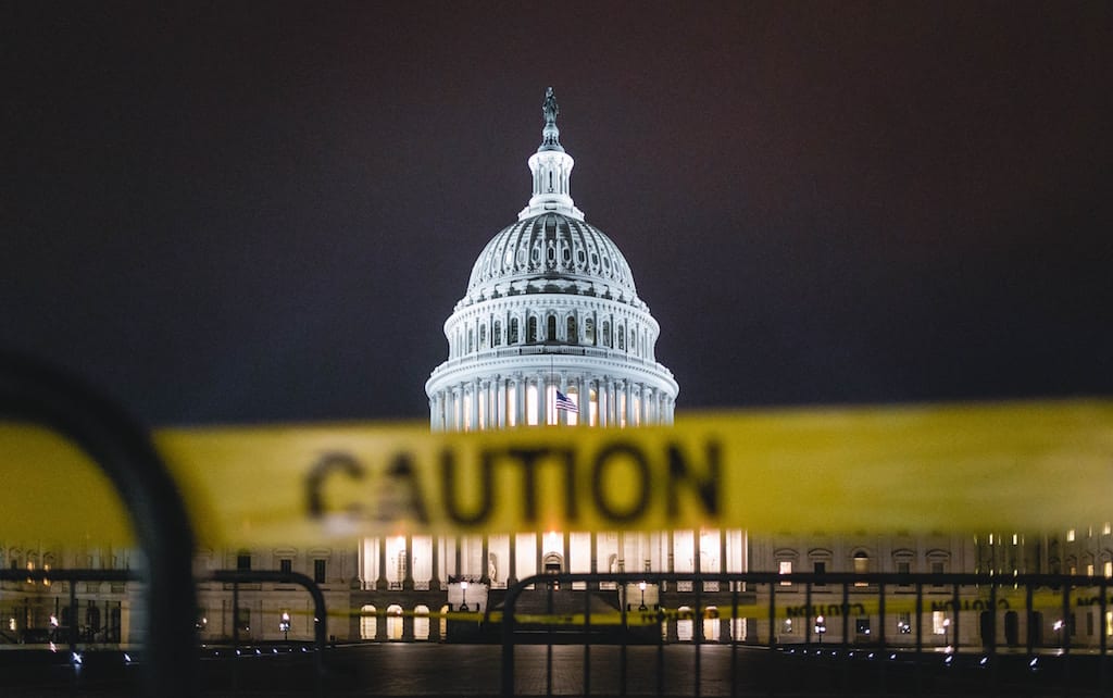 US Capitol building at night with slightly out of focus yellow caution tape in the foreground.