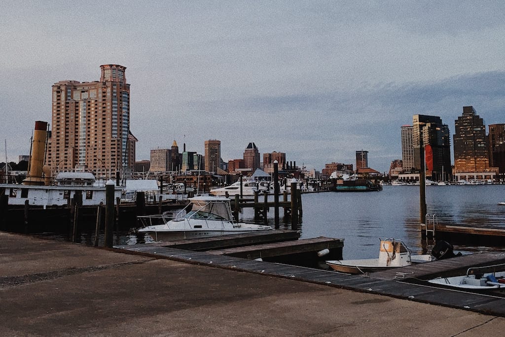 View of Baltimore's Inner Harbor taken from the waterfront. Boats and tall buildings in view.