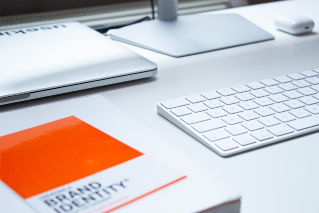 brand guidelines laying on a desk next to a mac computer