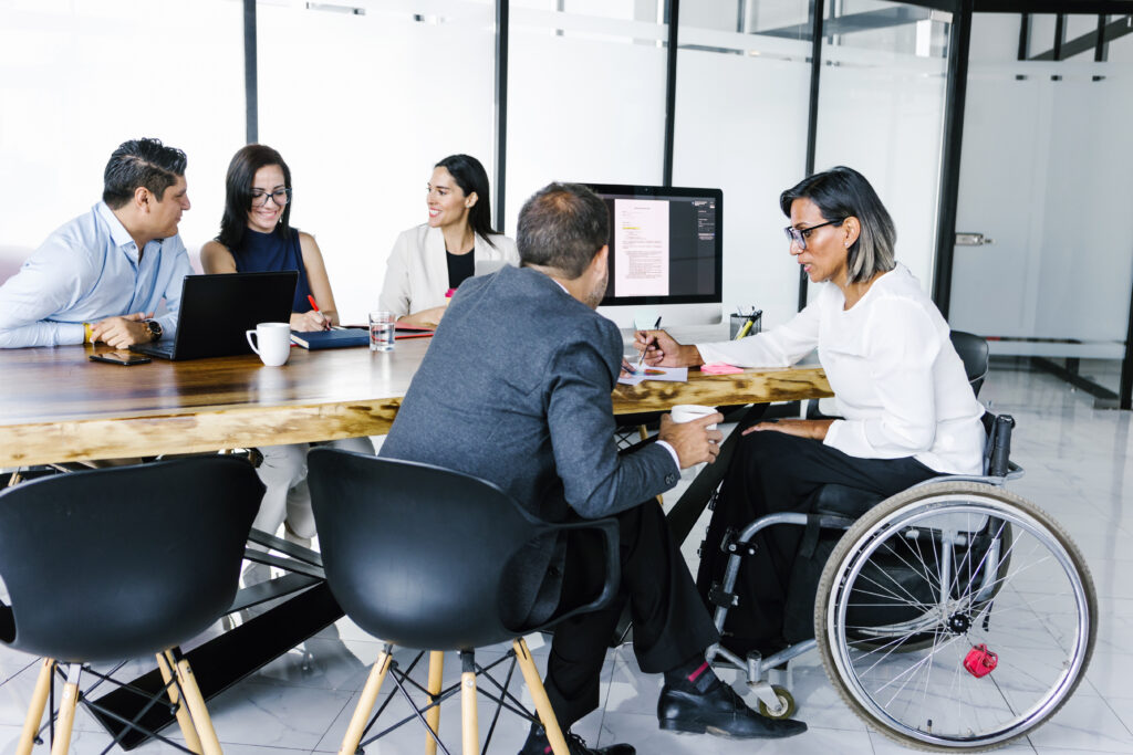 A group of people, including a woman in a wheelchair, working at a conference table